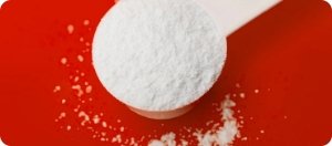 Close-up of L-Arginine scoop on red background, representing key natural ingredient in Manboa male enhancement formula.