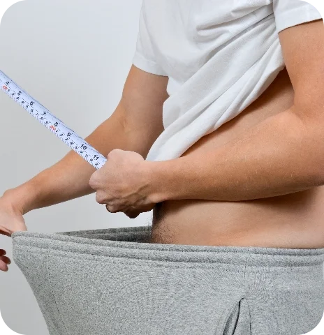 Man with tape measure on pants, humorously depicting size gains from Manboa.