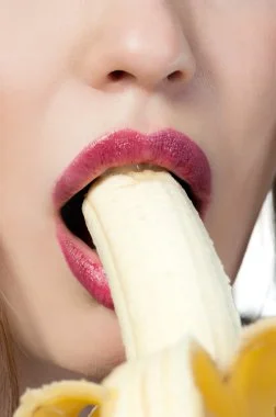Humorous stock photo of woman eating banana, playfully nodding to Manboa male enhancement fun.